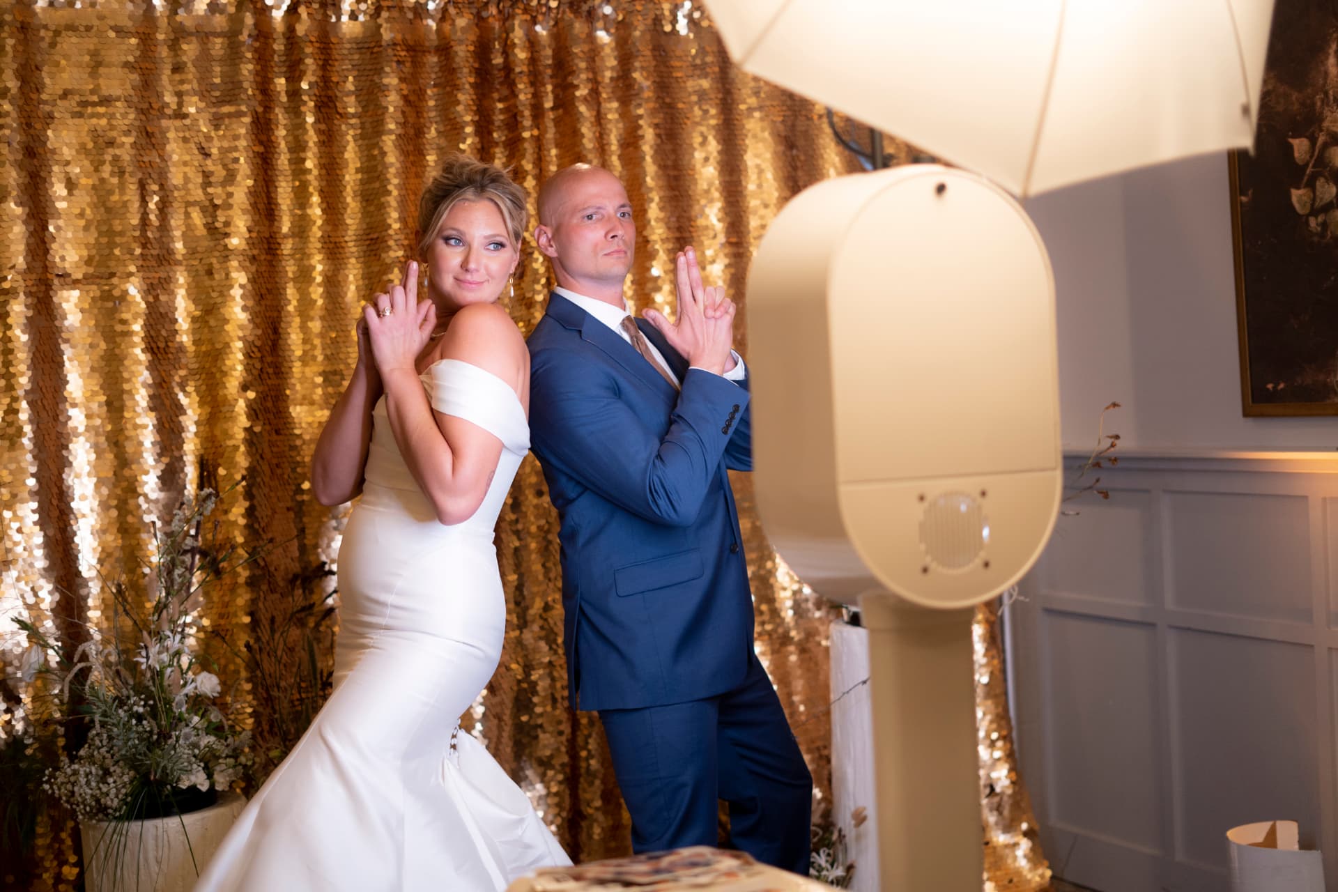 Bride and groom posing at the DSLR photo booth against a gold sequin backdrop