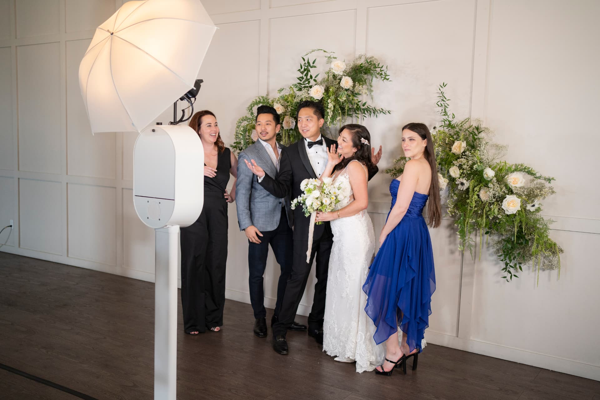 Wedding party posing at the DSLR photo booth beside a floral wall