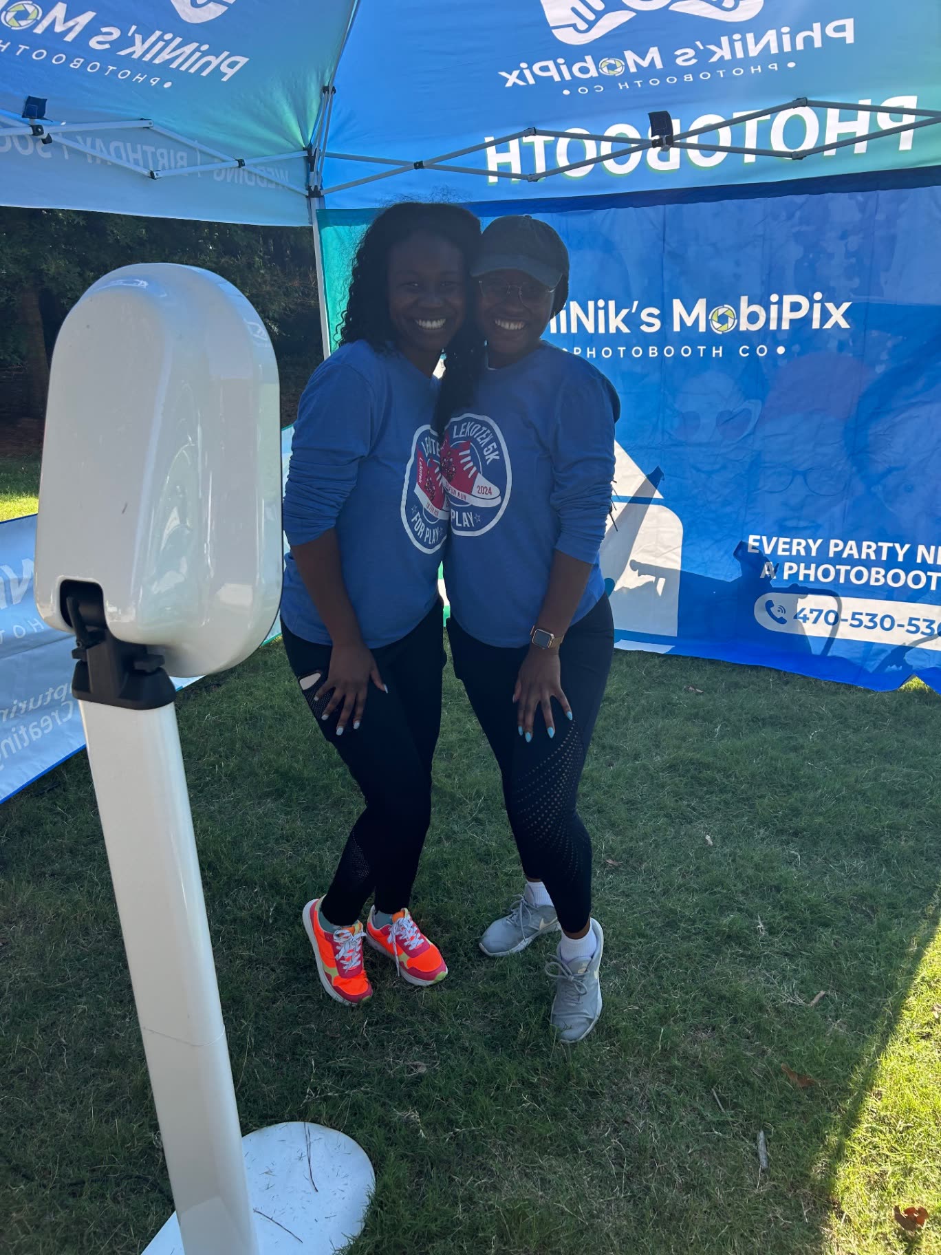Two runners hugging at the MobiPix booth tent during a charity 5K