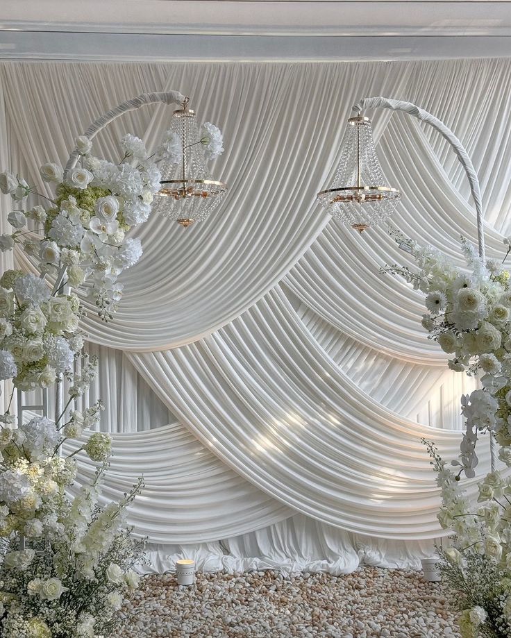 Custom white drapery backdrop with chandeliers and white florals